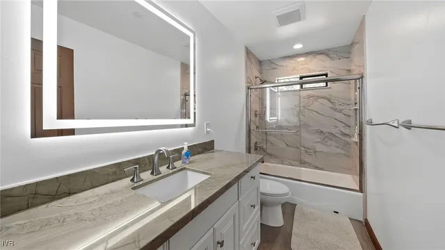 a bathroom with a granite countertop sink a toilet and shower