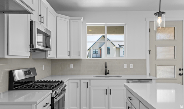 2415 North Ribe Lane Lehi, UT 84048 - Photo 5 of 17 Kitchen featuring white cabinets, stainless steel appliances, decorative light fixtures, backsplash, and light stone counters