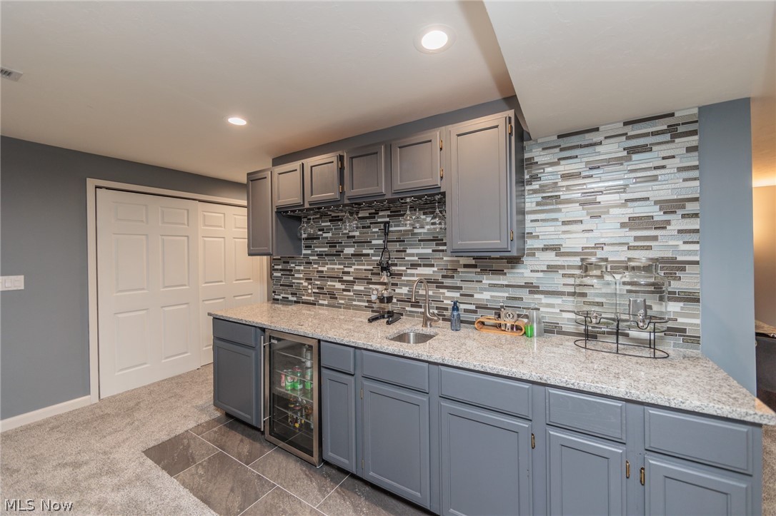 32883 Walnut Drive Avon, OH 44011 - Photo 26 of 34 Kitchen featuring tasteful backsplash, dark tile floors, beverage cooler, light stone countertops, and sink