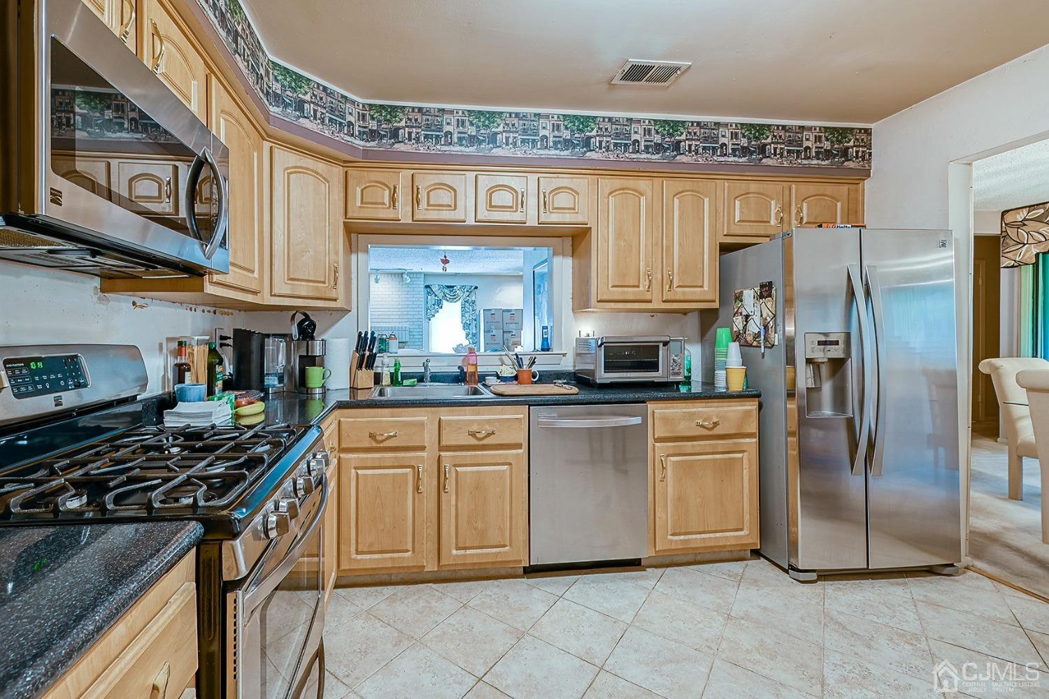 a kitchen with stainless steel appliances granite countertop a stove top oven a refrigerator and cabinets
