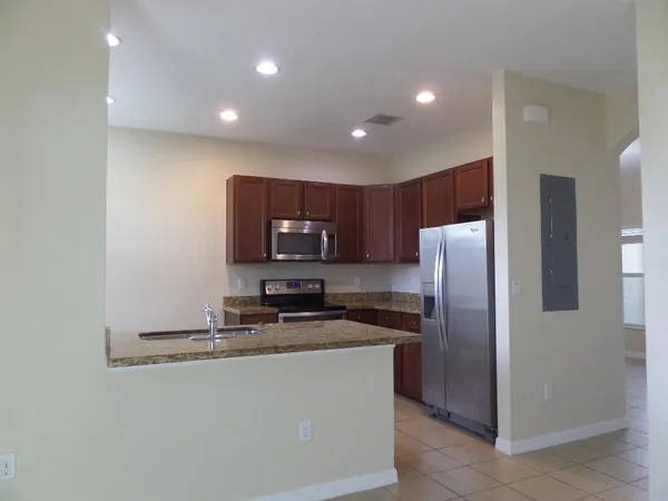 a kitchen with stainless steel appliances granite countertop a refrigerator a stove a sink and a microwave