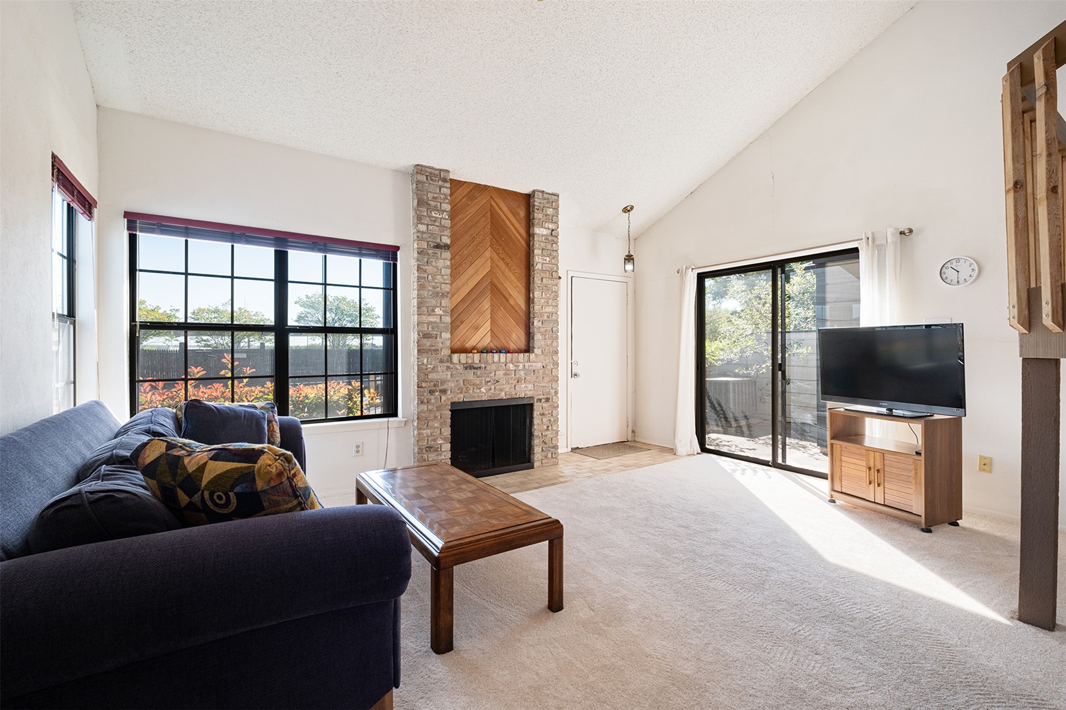 1748 Ohlen Road, Unit 16 Austin, TX 78757 - Photo 7 of 38 Living area with a high textured ceiling, light carpet, and a fireplace