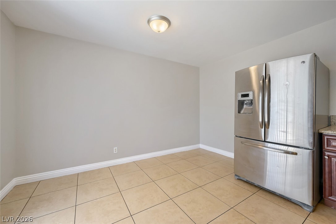 6321 Portola Road Las Vegas, NV 89108 - Photo 10 of 29 Functional kitchen area features tile flooring, a stainless steel refrigerator, and ample space for dining.