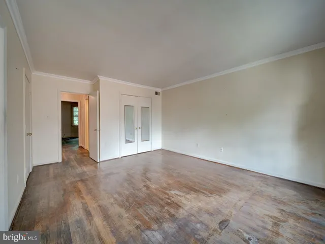 a view of an empty room with wooden floor and closet