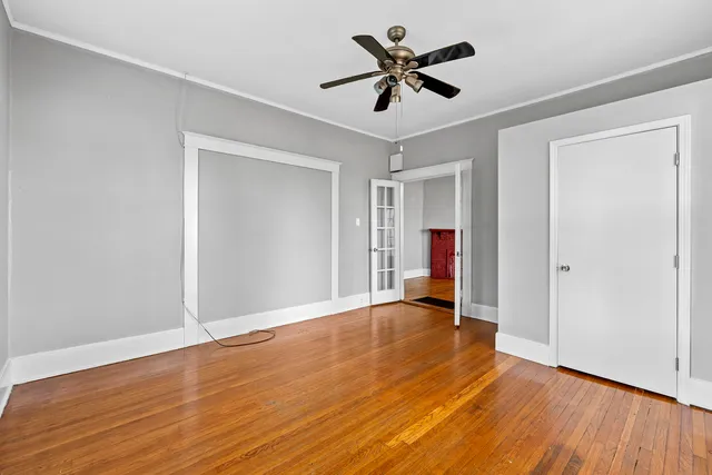 a view of empty room with wooden floor and ceiling fan