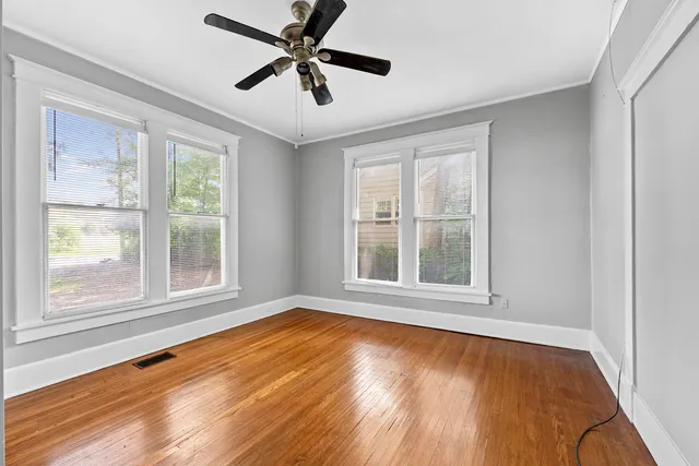 a view of an empty room with wooden floor and a window