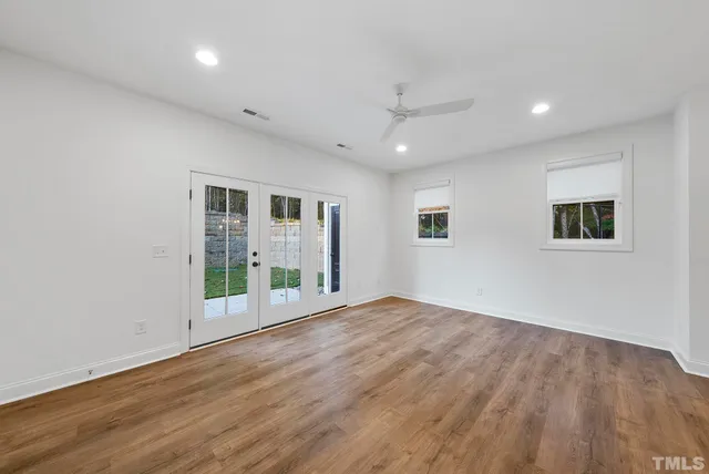 a view of an empty room with a window and wooden floor