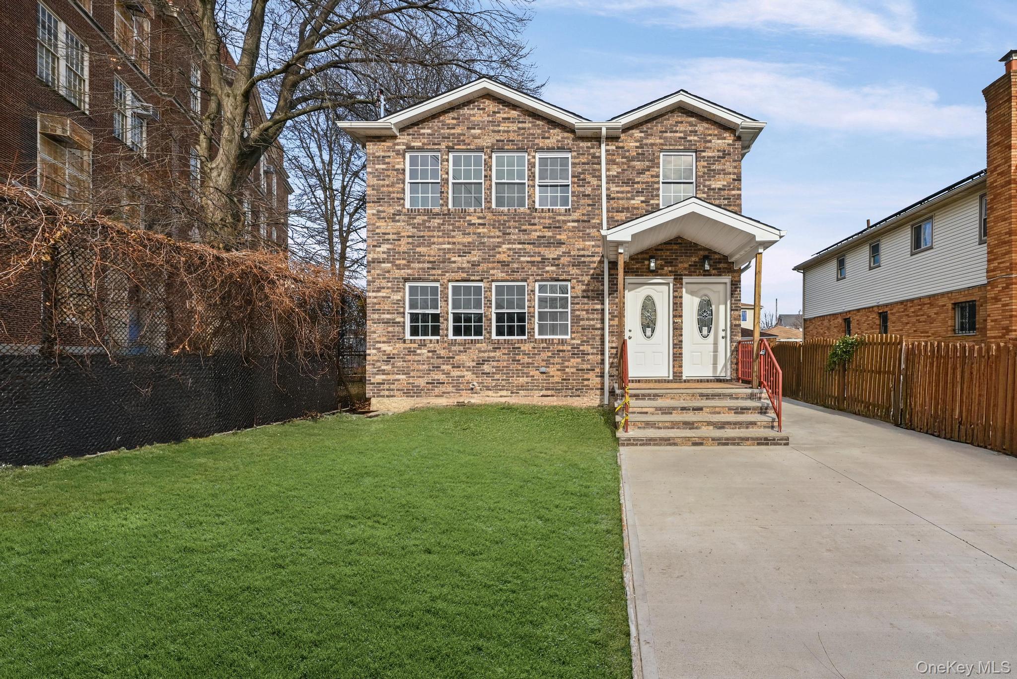 a view of a brick house with a yard and plants