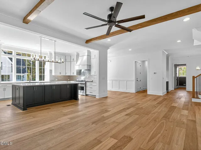 a kitchen with stainless steel appliances granite countertop a sink a stove a refrigerator and island with wooden floor