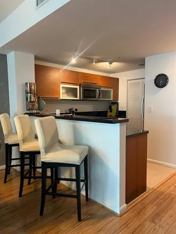 a kitchen with stainless steel appliances kitchen island granite countertop a table chairs and a wooden floor
