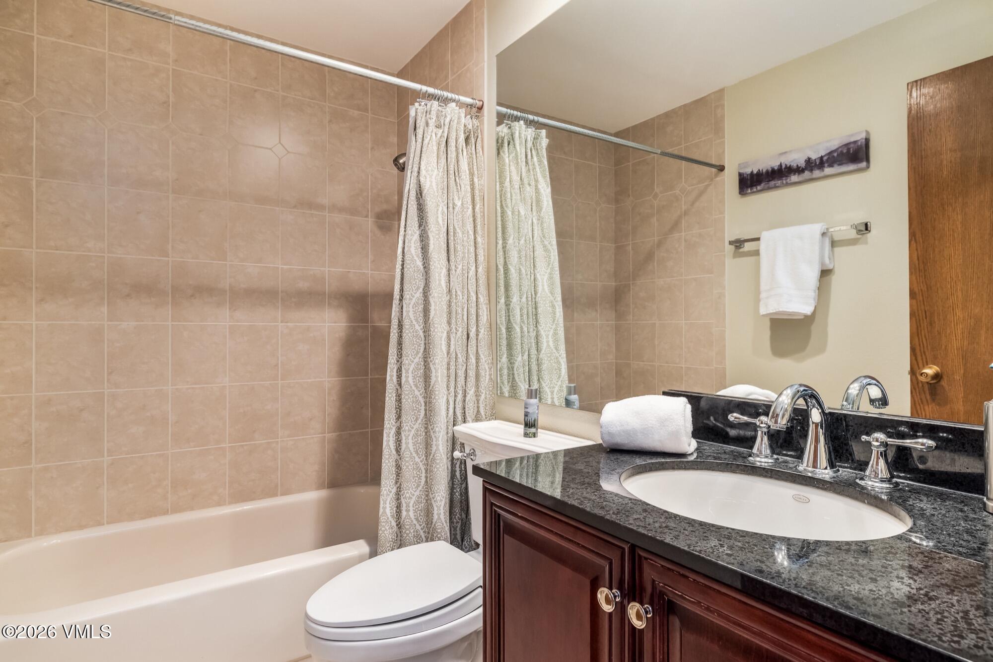 137 Benchmark Road, Unit 513 Avon, CO 81620 - Photo 26 of 31 a bathroom with a granite countertop sink toilet a mirror and shower