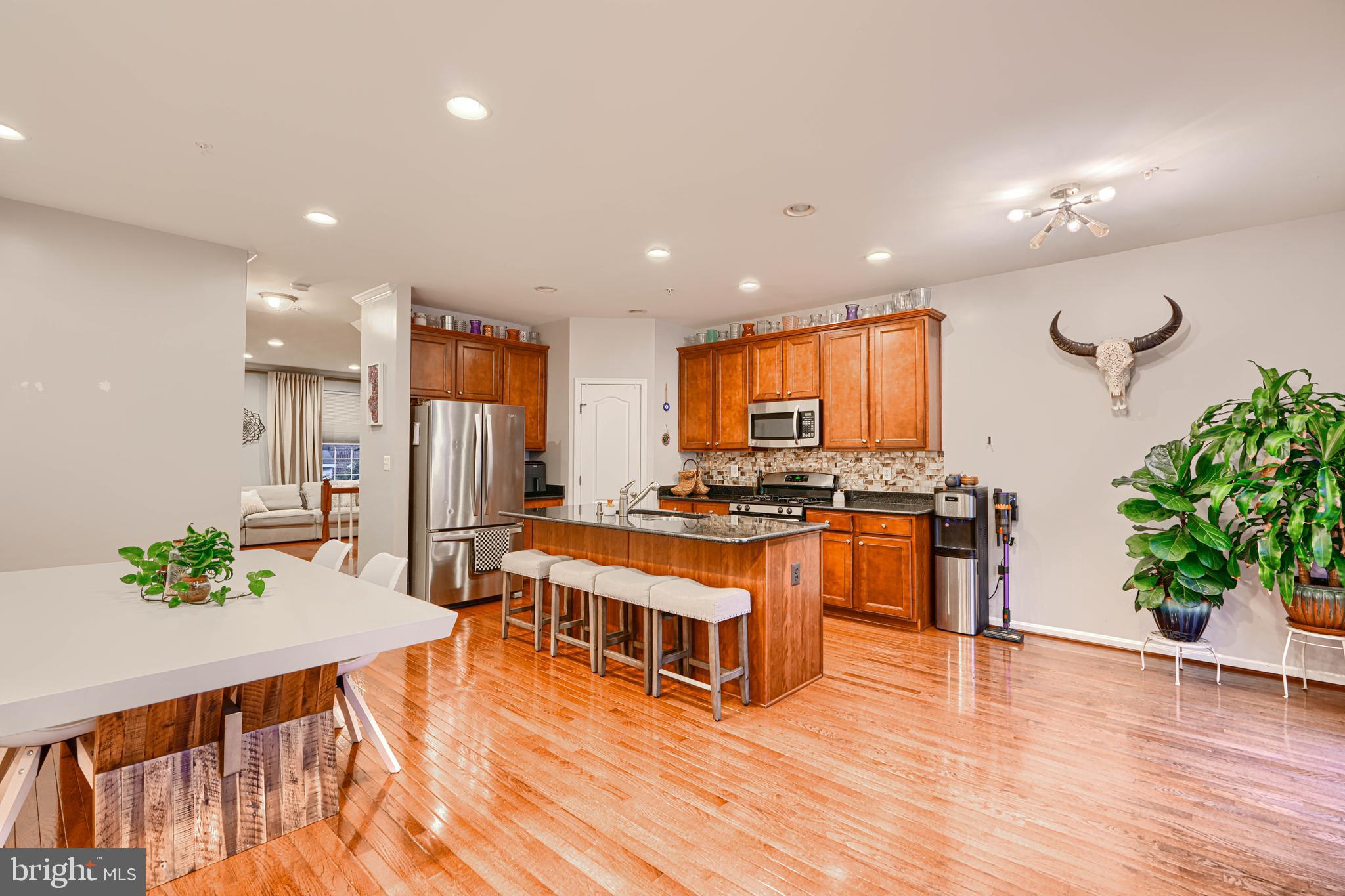 2642 Shade Branch Road Hanover, MD 21076 - Photo 12 of 29 a large white kitchen with stainless steel appliances granite countertop a stove a sink a refrigerator and a dining table with wooden floor
