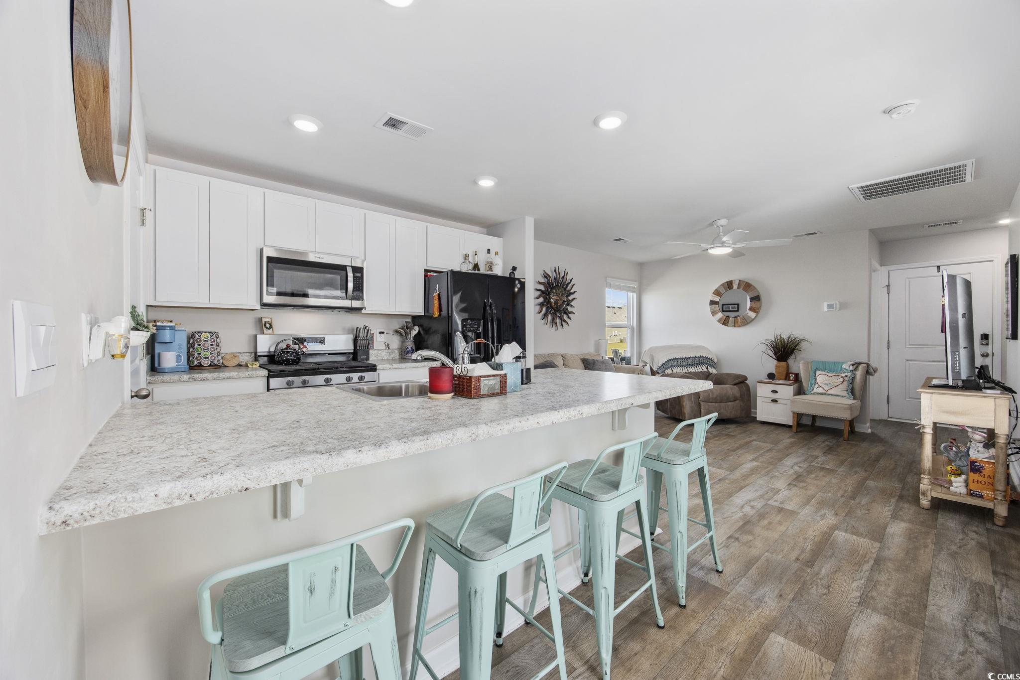 924 Akron Street Conway, SC 29526 - Photo 16 of 37 Kitchen featuring stainless steel appliances, white cabinets, a breakfast bar area, recessed lighting, and wood finished floors