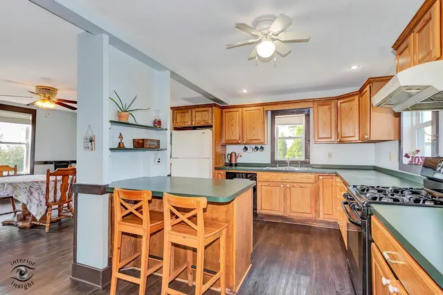 a kitchen with stainless steel appliances granite countertop a stove top oven a sink a dining table and chairs with wooden floor