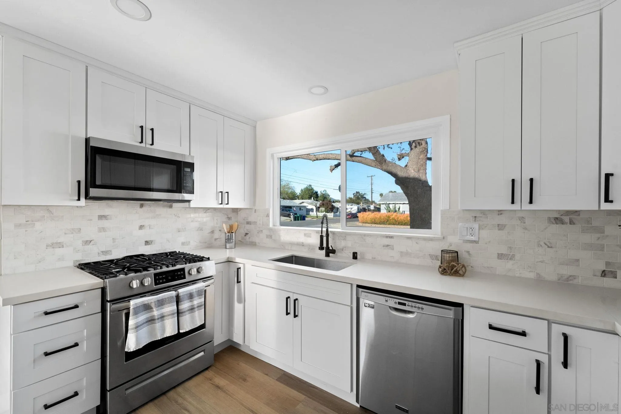 9511 Nicole Way Santee, CA 92071 - Photo 9 of 27 a kitchen with white cabinets a sink and a stove with wooden floor