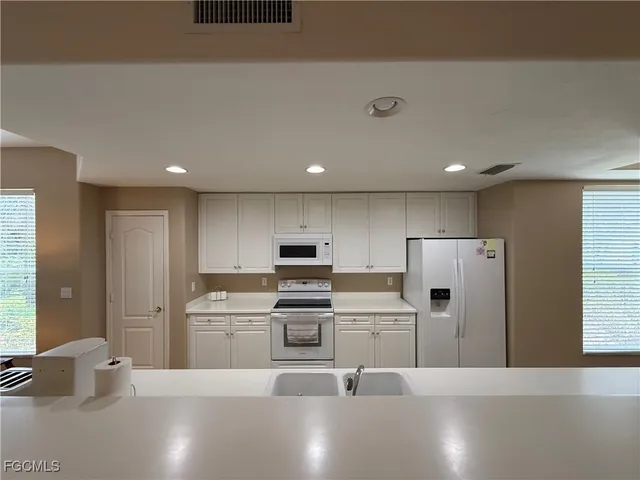 a living room with stainless steel appliances furniture a rug and a kitchen view