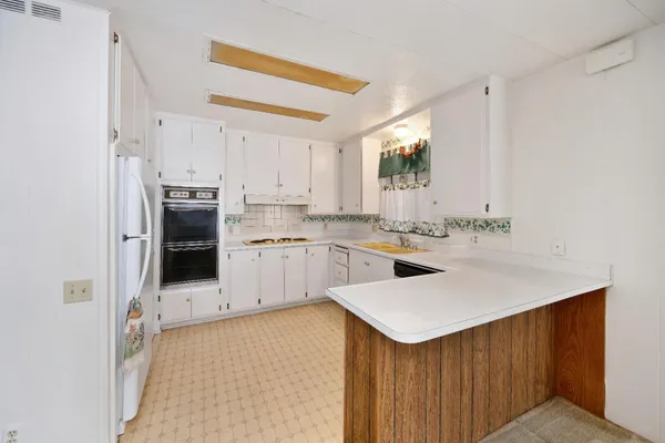 a kitchen with a sink a stove a refrigerator and white cabinets