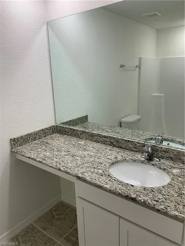 a bathroom with a granite countertop sink and a mirror