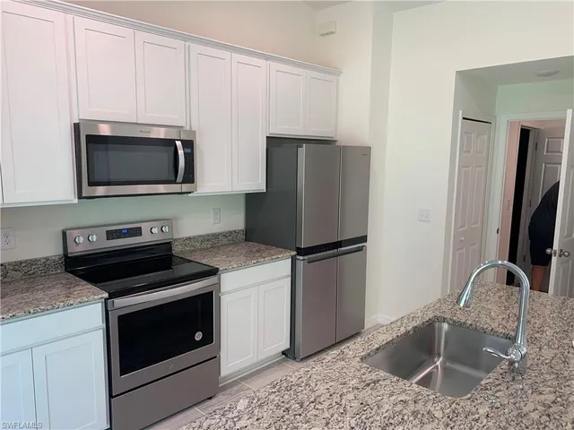 a kitchen with granite countertop a sink stove and refrigerator