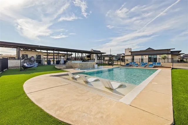 a view of swimming pool that has lawn chairs and a dining table under an umbrella