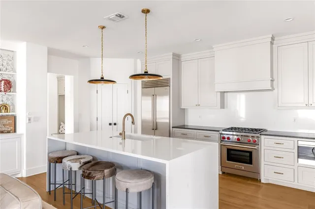 a kitchen with stainless steel appliances a stove a sink a island a refrigerator and cabinets