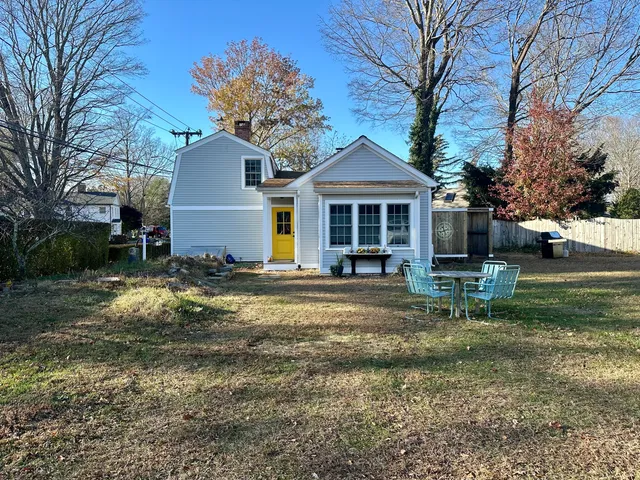 a front view of a house with a yard tree and outdoor seating