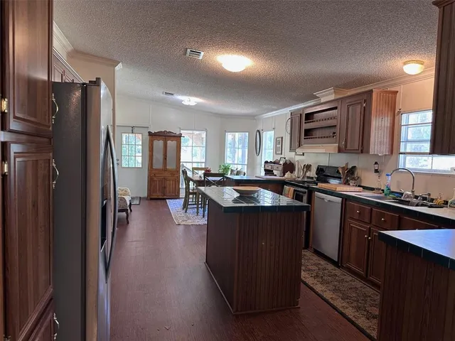 a kitchen with stainless steel appliances granite countertop a refrigerator a sink dishwasher a stove with wooden cabinets and a refrigerator