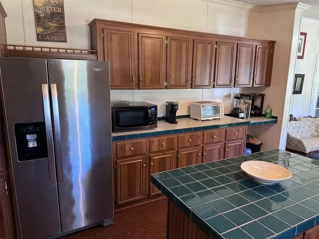 a kitchen with stainless steel appliances granite countertop a refrigerator a sink a stove a dining table and chairs