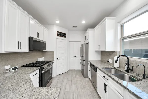 a kitchen with stainless steel appliances granite countertop a sink stove and refrigerator