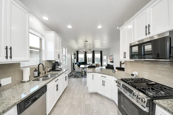 a large kitchen with stainless steel appliances granite countertop a lot of counter space and a sink