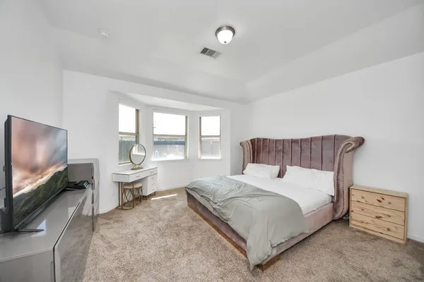 a spacious bedroom with a bed and large flat screen tv