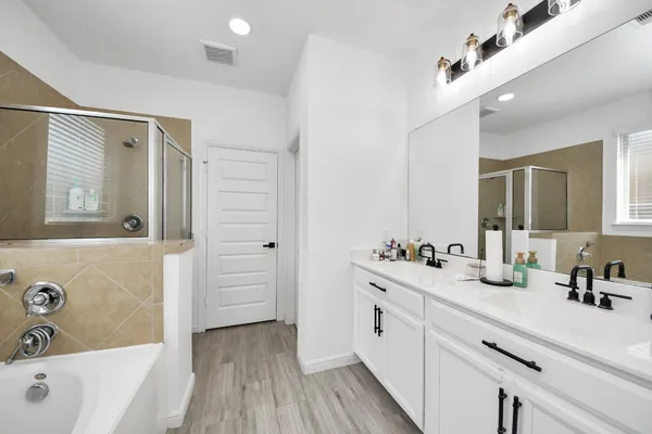a bathroom with a double vanity sink a mirror and a bathtub