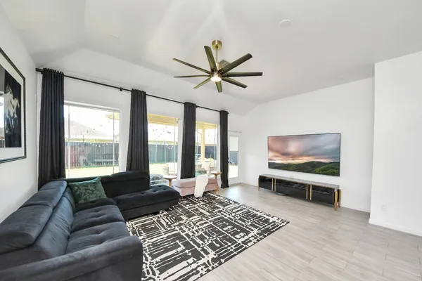 a living room with furniture a flat screen tv and a floor to ceiling window