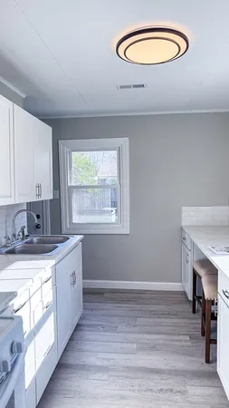 a kitchen with stainless steel appliances granite countertop a sink cabinets and wooden floor