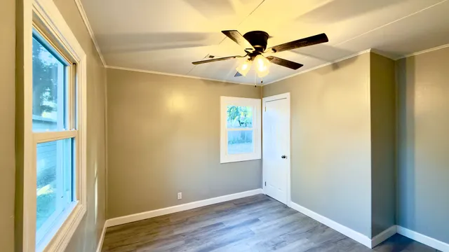a view of an empty room with wooden floor and a window