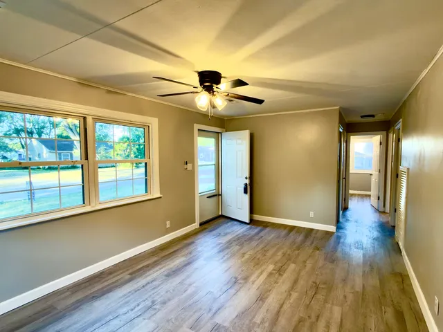 a view of an empty room with wooden floor and a window