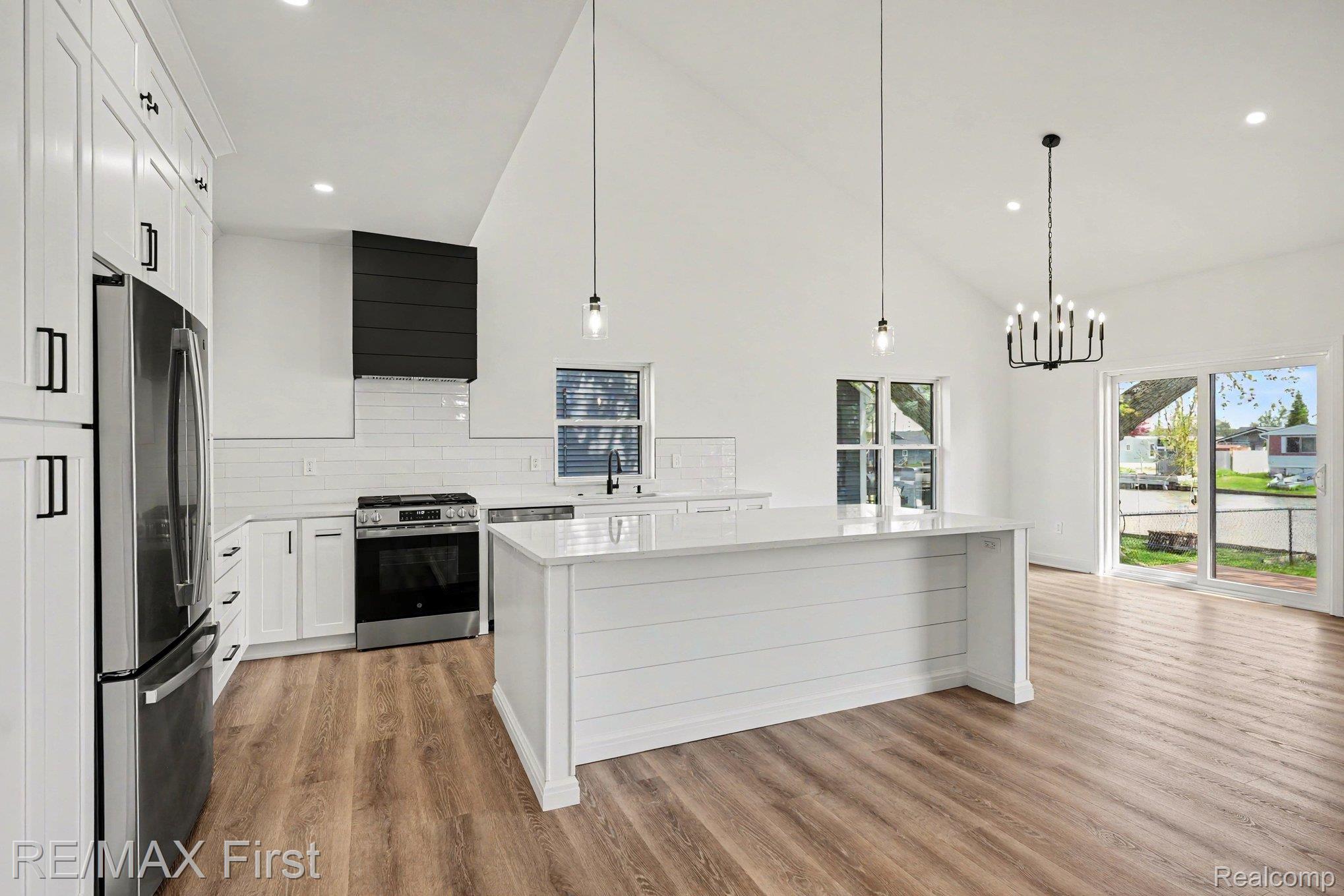 7424 Dyke Road Algonac, MI 48001 - Photo 13 of 31 Kitchen with white cabinets, stainless steel appliances, decorative backsplash, a kitchen island, and light wood finished floors