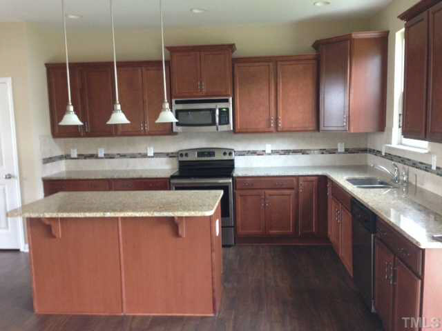 2728 Shepherd Valley Street Raleigh, NC 27610 - Photo 5 of 15 a kitchen with kitchen island granite countertop a sink a counter top space cabinets and stainless steel appliances