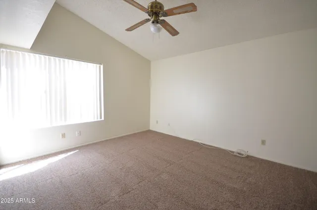 an empty room with a window and a fan