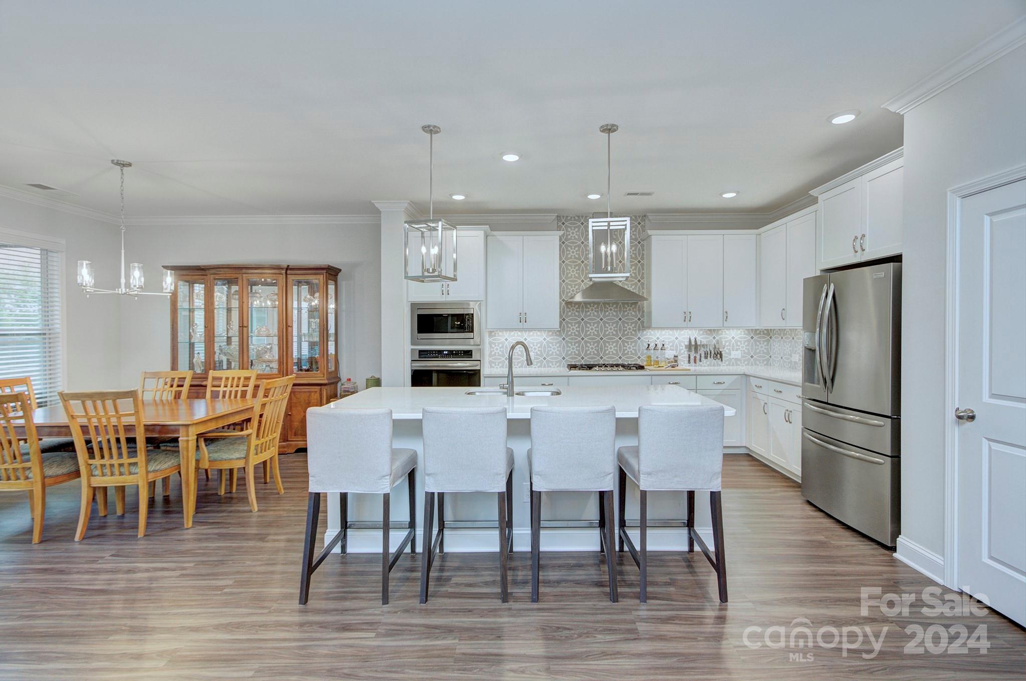 7047 Messina Road Fort Mill, SC 29707 - Photo 8 of 32 a kitchen with stainless steel appliances a dining table chairs stove refrigerator and cabinets