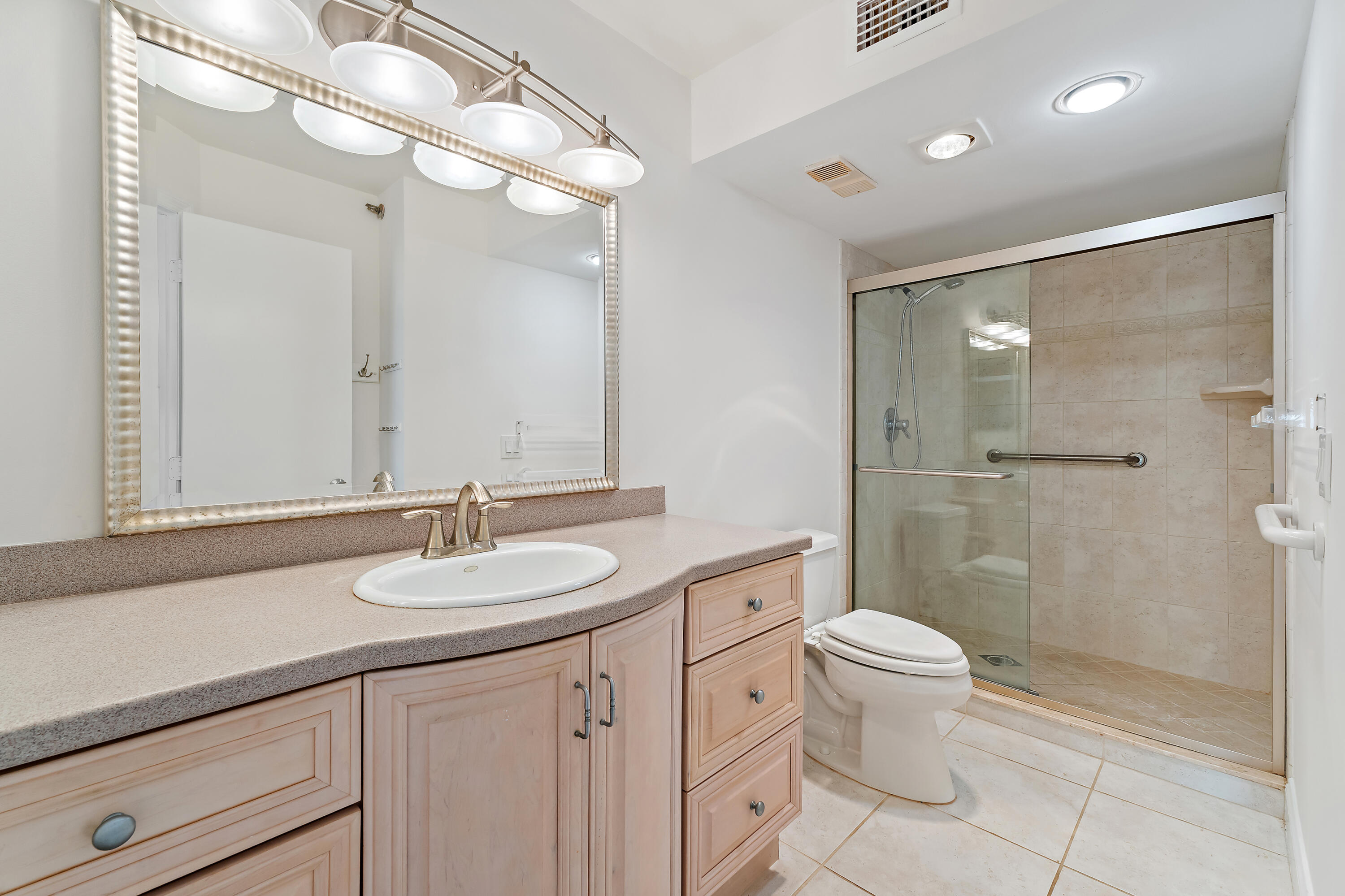 300 Ocean Trail Way, Unit 102 Jupiter, FL 33477 - Photo 16 of 30 a bathroom with a sink a toilet a mirror and shower