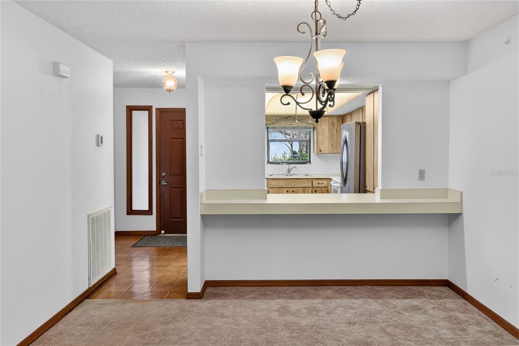 2025 Sylvester Road, Unit E1 Lakeland, FL 33803 - Photo 8 of 37 a dining room with wooden floor a chandelier a wooden table and chairs