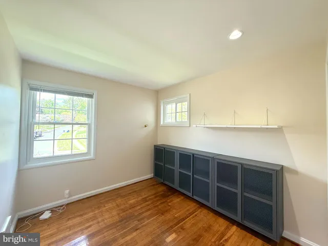 a view of an empty room with wooden floor and windows