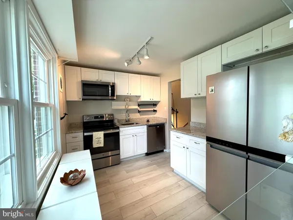 a kitchen with granite countertop stainless steel appliances cabinets a sink and a large window
