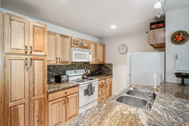 a kitchen with granite countertop a sink stove and refrigerator
