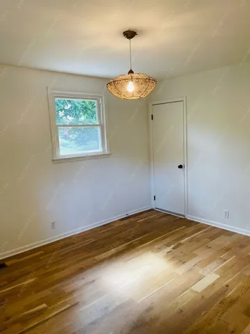 a view of an empty room with a chandelier fan