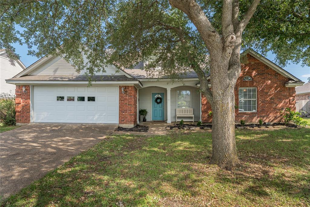 View of front of house featuring driveway, brick siding, a garage, and a front yard