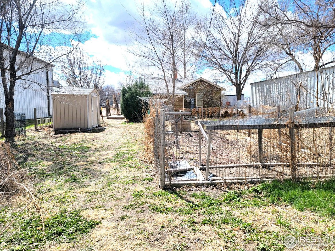 528 Phelps Street Sterling, CO 80751 - Photo 12 of 12 a view of a backyard with large trees and a barn