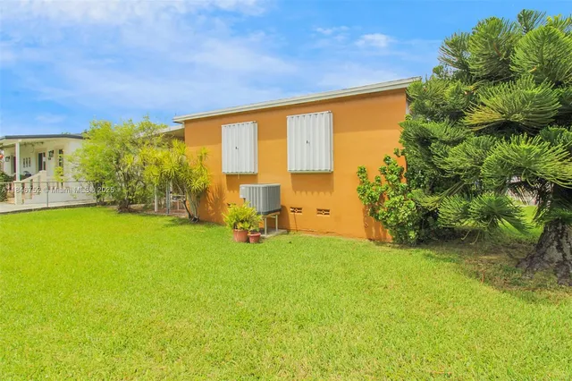 a view of yard with swimming pool outdoor seating and trees in the background