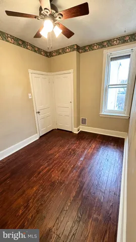 an empty room with wooden floor fan and windows